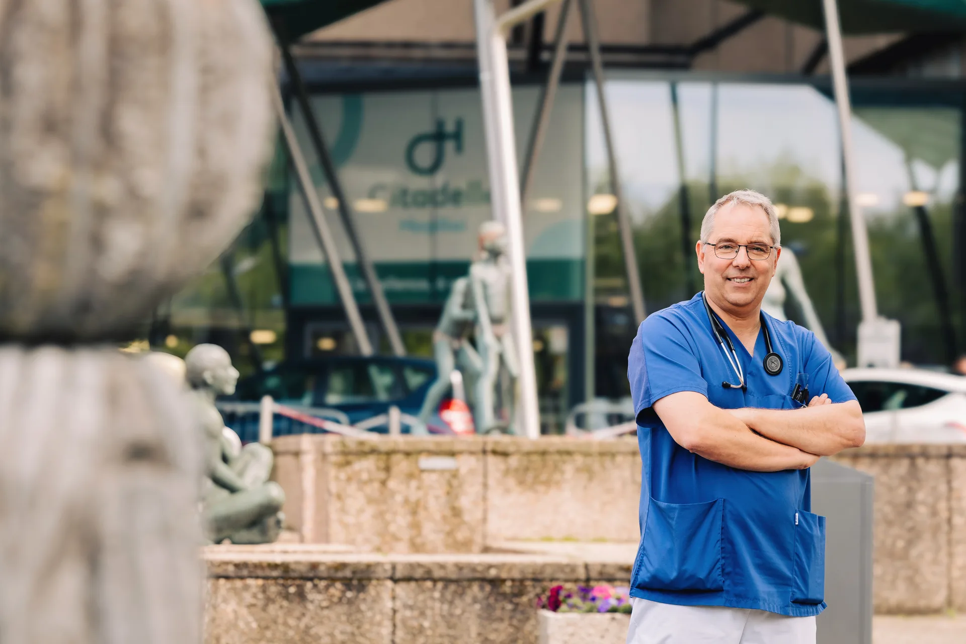 Médecin en tenue de bloc devant le CHR de la Citadelle à Liège — campagne photo médicale MSD